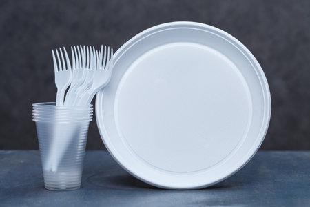 Plastic dishes, disposable tableware, plates, glasses, spoons, forks on a gray background. Caring for the environment. The problem is recycling. Reuse, safe planet, environmental concept.の写真素材