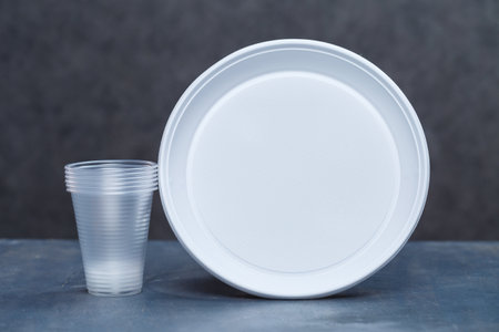 Plastic dishes, disposable tableware, plates, glasses, spoons, forks on a gray background. Caring for the environment. The problem is recycling. Reuse, safe planet, environmental concept.の写真素材