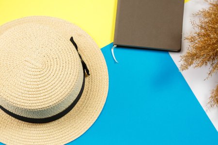 Women's accessories notebook, hat, lifestyle, woman, rest, with dry grass, decor, flat lay, color style in the background. Travel, tourism concept. Beach accessories top view.の写真素材