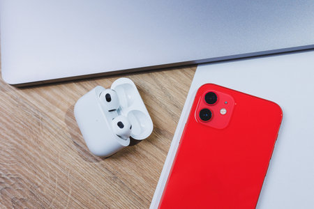 Newest red smartphone and wireless headphones in charging case on white background