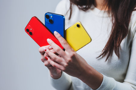 New bright phones in the hands of a woman. Hands of a woman holding several smartphones.の写真素材