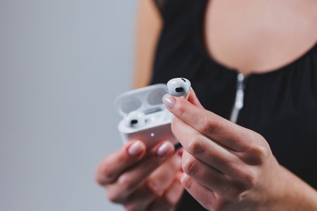 White wireless headphones in a woman's hand, close-up. Headset with charging case.の写真素材