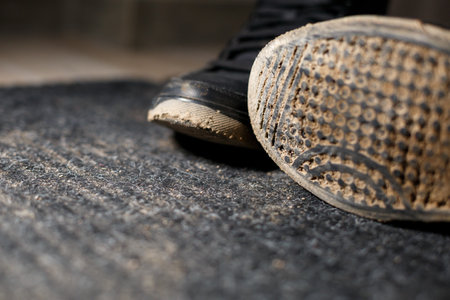 dirty shoes standing on a black carpet with a scattered swampの写真素材