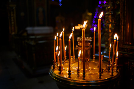 Many burning candles stand in a golden stand in the church. Selective focusの写真素材