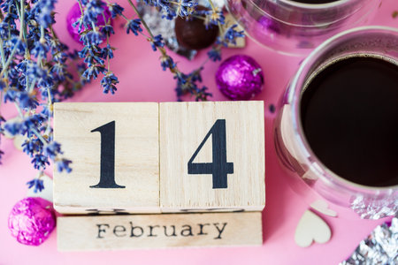 World Valentine's Day. Wooden calendar with date 14 February on pink background with coffee and sweetsの写真素材