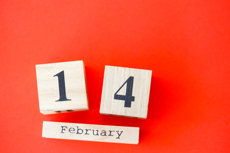 Wooden calendar with the date of February 14 on a bright red background. Romantic date. Valentine's day concept. Top view, copy space.の写真素材