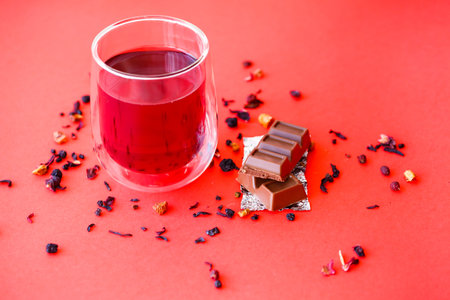 Hot hibiscus tea in a transparent glass with a double bottom on a red backgroundの写真素材