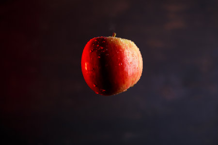 red-yellow large apple, flooded with water on a dark backgroundの写真素材