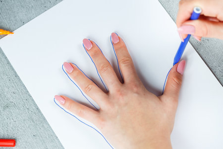 Girl draws with multi-colored felt-tip pens on white paper
