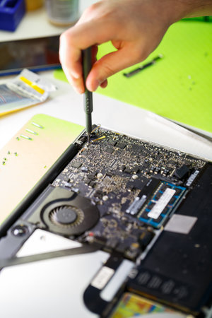 man cleans a laptop with a special tool from dust. Repair and maintenance of laptops and PCs Advertising services for the repair of electronics and devices.の写真素材