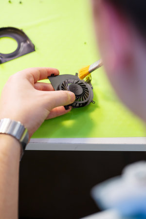 man cleans a laptop with a special tool from dust. Repair and maintenance of laptops and PCs...
