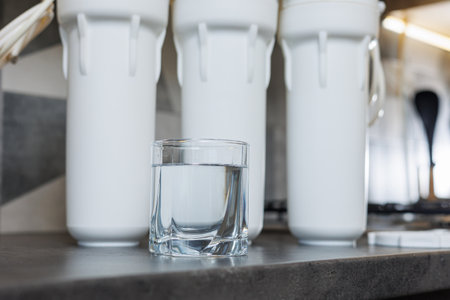 A glass of filtered water. Water filtration system with replaceable cartridges. A system in the apartment with three tanks for cleaning tap water.の写真素材