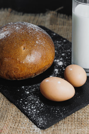 Delicious round rye bread with milk and eggs on a dark background. Crispy fresh bread.