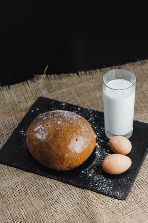 Delicious round rye bread with milk and eggs on a dark background. Crispy fresh bread.の写真素材