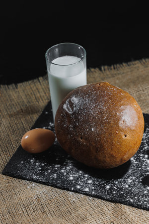 Delicious round rye bread with milk and eggs on a dark background. Crispy fresh bread.
