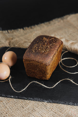 Baking homemade bread, natural agricultural products. Healthy and tasty pastries. Whole grain bread, eggs, flour. Close up, dark backgroundの写真素材