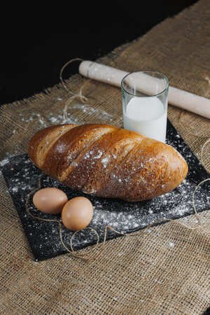 Delicious round rye bread with milk and eggs on a dark background. Crispy fresh bread.