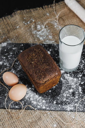 Delicious round rye bread with milk and eggs on a dark background. Crispy fresh bread.の写真素材