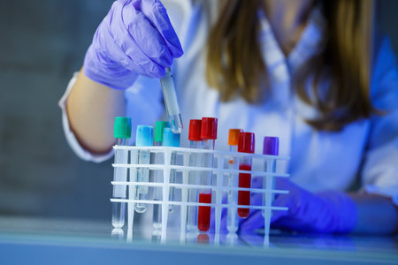 A medical professional, laboratory assistant, doctor performs an analysis in a laboratory, uses test tubes, a pipette and a petri dish for the presence of bacteria in the human bodyの写真素材