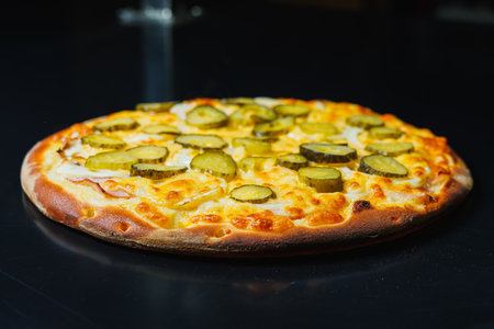 Sliced pizza with cucumber and meat, tomato sauce, mozzarella, onion and edge of dough, filled with cream cheese on a black backgroundの写真素材