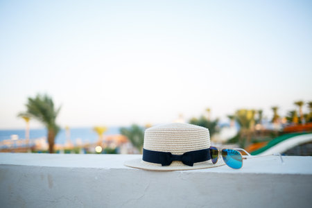 Women's summer hat and glasses lie on the terrace overlooking the seaの写真素材