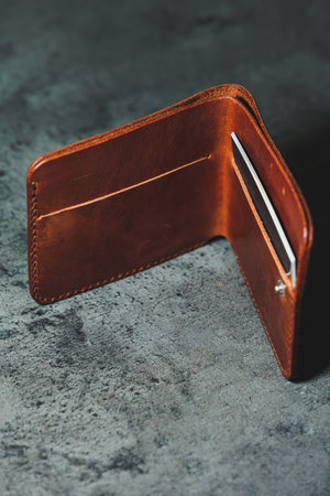 Stylish handmade brown leather men's wallet on a gray background. Product made of genuine leather.