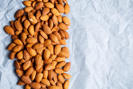 Delicious roasted sweet almonds lie in a large heap, nuts close-up.の写真素材
