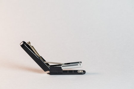 black stapler for fastening papers on a gray background