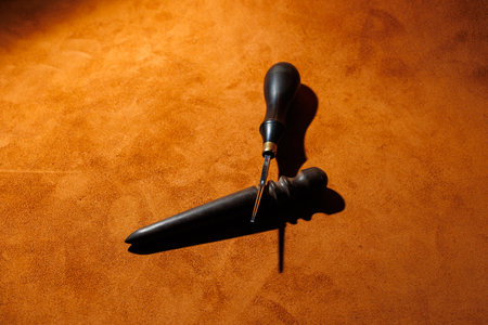Production of handicrafts from genuine leather. Tools for making leather goods and pieces of brown leather. Production of leather products. View from aboveの写真素材