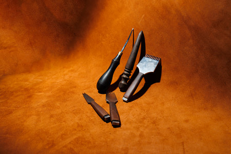 Production of handicrafts from genuine leather. Tools for making leather goods and pieces of brown leather. Production of leather products. View from aboveの写真素材