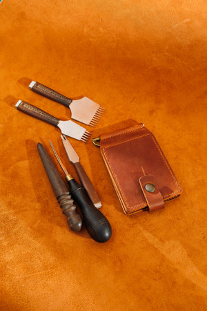 Production of handicrafts from genuine leather. Tools for making leather goods and pieces of brown leather. Production of leather products. View from aboveの写真素材