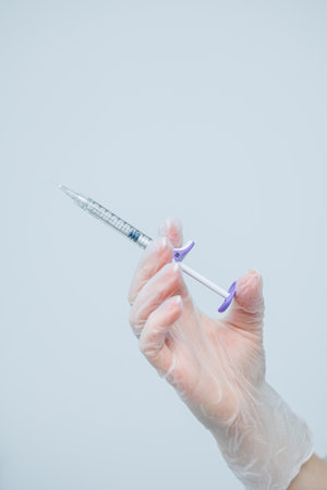 Female hand in gloves with syringe in hand. Syringe for injections in cosmetologyの写真素材