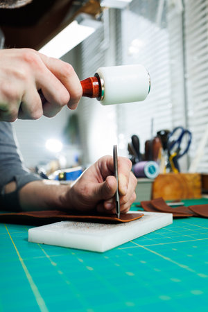 Hands of a professional craftsman make a leather wallet new, clean genuine leather wallet, close-up...