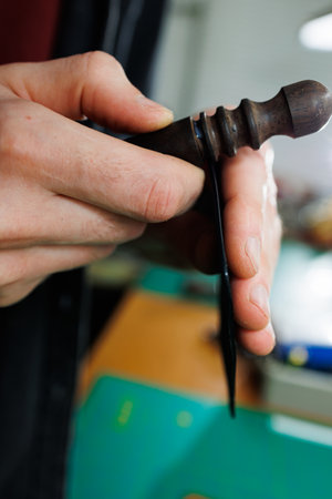 The hands of the master sew handmade leather products. Men's hands connect the parts, creating...