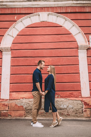 Young couple in love on the background of a red wall. Happy married couple on a walk in the cityの写真素材