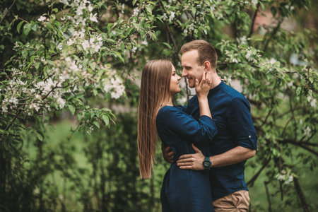 Handsome young guy with a girl stand in the spring garden. Romantic couple are walking in the park. Happy relationship conceptの写真素材