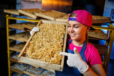 The girl works on the production of spaghetti. Making noodles. Pasta factory. Stage production of...