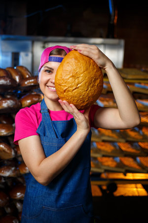 A worker works in a bakery. She puts bread on a shelf. Fresh crispy bread close-up