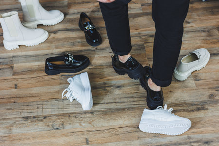 A woman chooses shoes against a brick wall. Several pairs of women's leather shoes