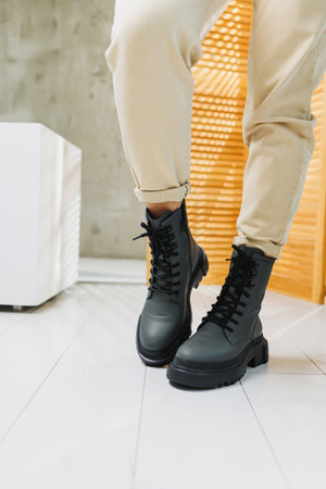 Fashionable women's stylish leather boots. Green women's genuine leather boots on feet close-up. New collection of winter shoes for stylish girls.の写真素材