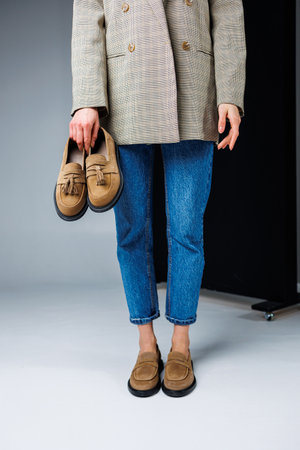 Casual women's fashion. Classic shoes for women. Slender female legs in trousers and brown stylish casual loafers. Women's comfortable summer shoes.の写真素材