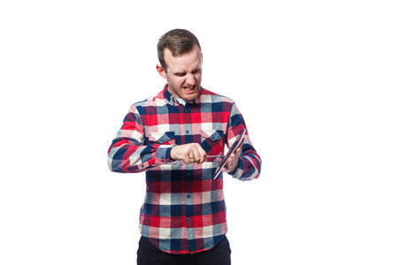 white-skinned male freelancer, repairman, scratches the protective film on the tablet screen and removes it. wearing a shirt. Emotional portrait. Isolated on white backgroundの写真素材