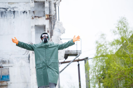 A man in a protective mask and protective clothing explores a dangerous radioactive area. destroyed housesの写真素材
