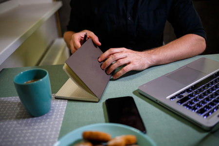 A man makes a record with a pen in a notebook. A book for recording important matters. Diary of a...