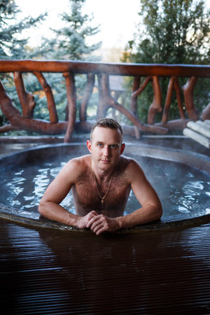 Young man in the pool with hot water on the terrace, spa body treatments. Outdoor Jacuzzi. Jacuzzi...
