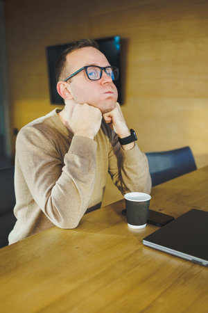 Top view of man in casual clothes with coffee sitting at workplace using netbook while working during working day. A successful businessman works on a laptop computerの写真素材