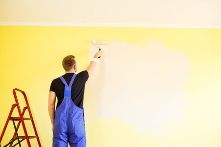 Male specialist paints the wall with paint indoors, repair conceptの写真素材