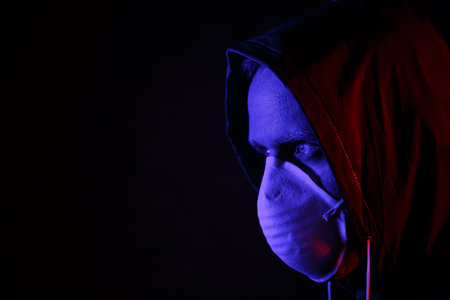 A man in a mask and chemical protection suit in red and blue light. Fight against the virus. COVID-19の写真素材