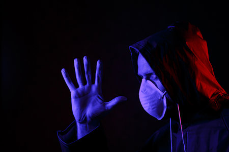 A man in a mask and chemical protection suit in red and blue light. Fight against the virus. COVID-19の写真素材