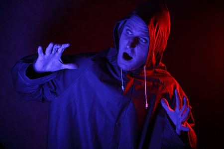 A man in a protective suit in a dark room. Halloween image concept. Virus protection. Illuminated...